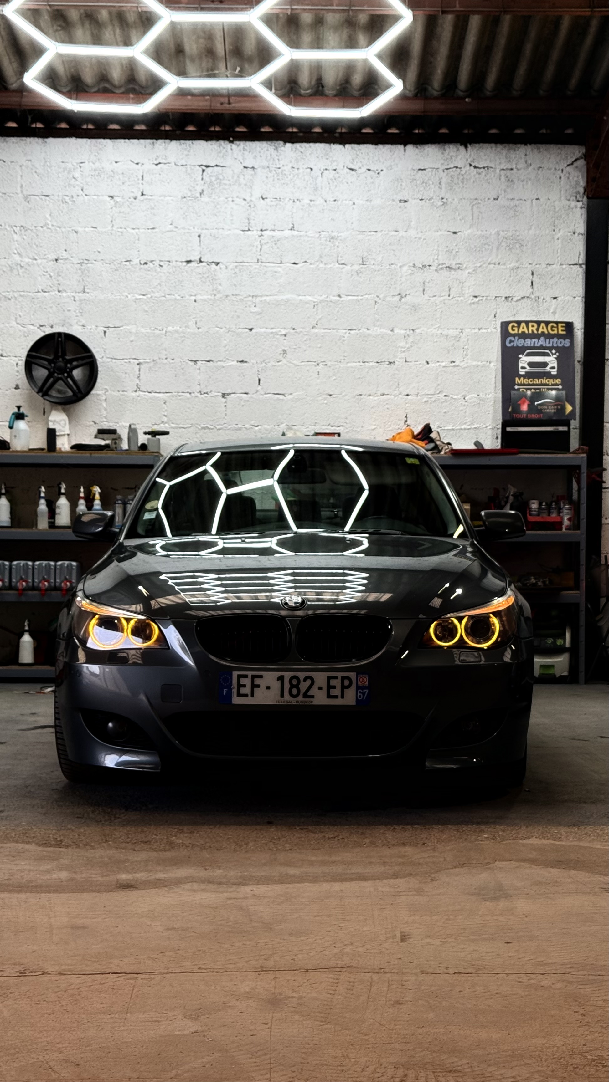 BMW E60 noire avec angel eyes jaunes en atelier CleanAutos Colmar