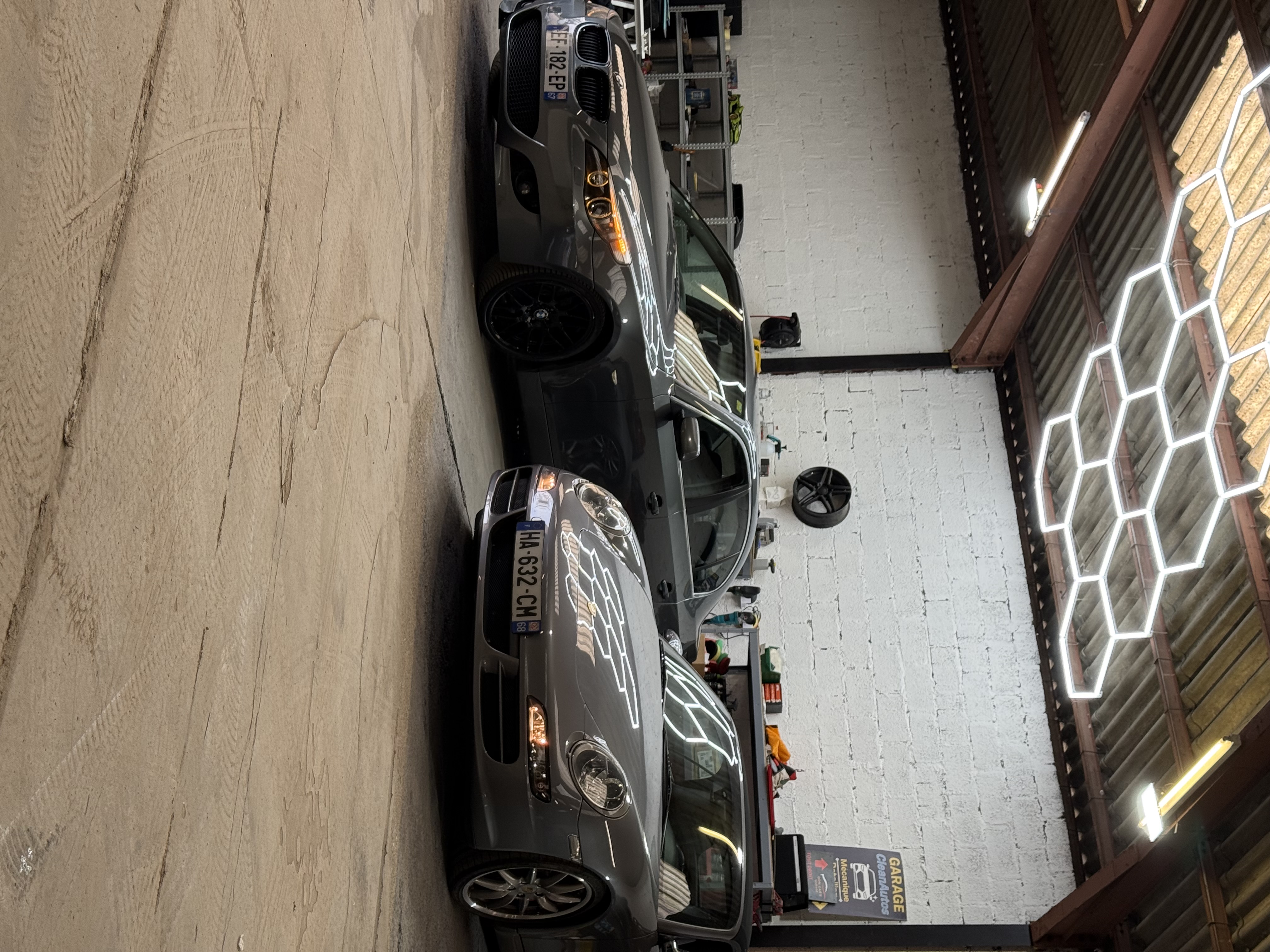 BMW E60 et Porsche 911 sous l'éclairage LED hexagonal de l'atelier